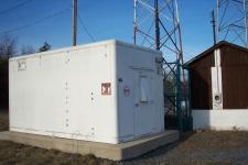 The equipment building of a small, unlabeled radio tower.
